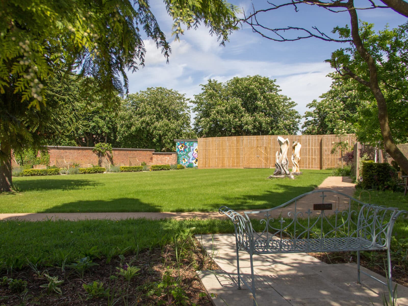 Benches with commemorative plaques look onto the Secret Garden lawn at Glenfield Hospital