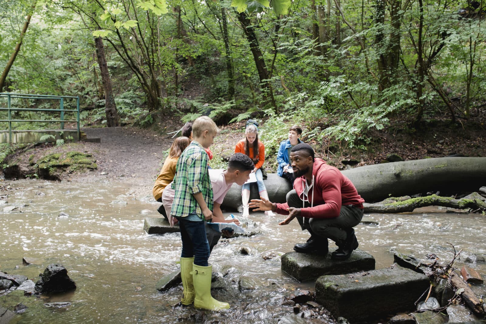 Group of school children on a field trip. They are standing in a river. Credit iStore