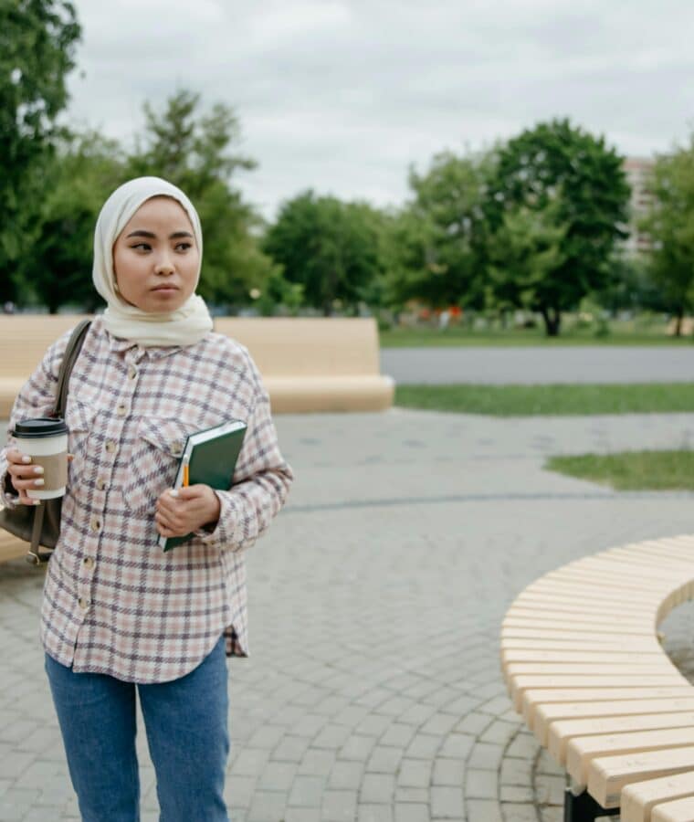 Young woman in head scarf walking near seating area in park. Credit Pixabay